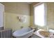 A vintage-style bathroom featuring a classic clawfoot tub, yellow tiling, and patterned wallpaper at 143 Reid St, Rock Hill, SC 29730