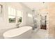 Bright bathroom features a glass-enclosed shower, soaking tub, and vanity with elegant fixtures and patterned wallpaper at 1922 Hamorton Pl, Charlotte, NC 28205