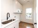 Well-lit laundry room with a stainless steel sink, shaker cabinets, and a convenient window for natural light at 1922 Hamorton Pl, Charlotte, NC 28205