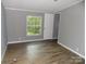 A bedroom features wood-look flooring, a window offering outside views, and neutral gray wall paint at 2130 Babbling Brook Ln, Gastonia, NC 28052