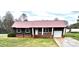 Charming single story home featuring dark siding, metal roof, a cozy front porch, and attached garage at 2180 Grace Church Rd, Salisbury, NC 28147