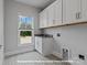Bright laundry room with white cabinets, patterned floor, sink, and a view from the window at 276 Gilead Rd, Huntersville, NC 28078