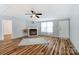 Open living room features wood floors, a ceiling fan, and a cozy fireplace, perfect for relaxing and entertaining at 405 Briarwood Ct, Mount Holly, NC 28120