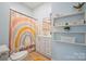 Bright bathroom with a rainbow shower curtain, white vanity, open shelving, and a cheerful design at 41 Selma Dr, Mooresville, NC 28115
