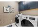Well-lit laundry room featuring modern washer/dryer, blue cabinets, and wall art at 411 Sunharvest Ln, Indian Trail, NC 28079