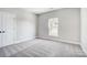 Neutral bedroom with light gray walls, carpeted floor, a window, and paneled interior door at 522 Fern Hill Rd # 17, Mooresville, NC 28117