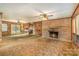 Comfortable living room featuring wood paneling, brick fireplace, ceiling fan, and an open floorplan connecting to the kitchen at 624 Flicker St, Concord, NC 28027