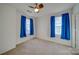 Well-lit bedroom with a ceiling fan and bright blue curtains on both windows at 746 Elders Story Rd, Fort Mill, SC 29708