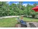 Backyard featuring a stone patio with outdoor seating, a red umbrella, a white fence, and mature trees for shade at 1017 Chalk Hill Ln, Charlotte, NC 28214