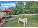 Lush backyard featuring a stone patio, outdoor furniture, a red umbrella, and a white picket fence for privacy at 1017 Chalk Hill Ln, Charlotte, NC 28214