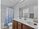 Bright bathroom with double vanity, large mirror, and a shower-tub combination featuring a blue patterned shower curtain at 1017 Chalk Hill Ln, Charlotte, NC 28214