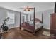 Spacious bedroom featuring a four-poster bed, ceiling fan, hardwood floors, and natural light from two windows at 1017 Chalk Hill Ln, Charlotte, NC 28214