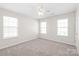 Well-lit bedroom with carpeted floors, ceiling fan, and three bright windows at 11122 Aprilia Ln, Cornelius, NC 28031