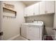 Well-lit laundry room with white washer and dryer, upper cabinets, and decorative shelving at 11810 Red Leaf Dr, Charlotte, NC 28215