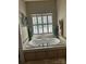 This bathroom features a bright window with shutters, a jetted tub, and neutral-toned tiling at 1308 Moonshadow Ln, Shelby, NC 28150