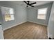 Sunlit bedroom with wood-look flooring, a ceiling fan, and two windows at 1946 Academy St, Charlotte, NC 28205