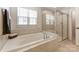 Relaxing bathroom showcasing a soaking tub with tile surround and a glass enclosed shower at 7027 Waterwheel St, Concord, NC 28025