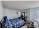 Bedroom featuring a black framed bed with blue striped bedding, plus black dresser and two fans at 7619 Woodknoll Dr, Charlotte, NC 28217