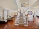 Bright foyer with hardwood floors, staircase with white railings, and an open view to the living and dining areas at 7719 Whisperingwood Dr, Harrisburg, NC 28075