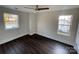 Bedroom with dark wood floors, ceiling fan, and two windows with neighborhood views at 8704 Moody Rd, Charlotte, NC 28215