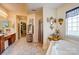 Warm bathroom with dual sink vanity, shower, garden tub and decorative art and florals at 10202 Little Whiteoak Rd, Charlotte, NC 28215