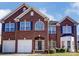 A red brick two-story home with blue shutters, an attached two-car garage, and manicured lawn at 10202 Little Whiteoak Rd, Charlotte, NC 28215