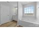 Bright bathroom with soaking tub, large window, white door, and white vanity with sink at 11331 Breezehill Ln, Charlotte, NC 28262