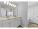 Bathroom with a double sink vanity, a large mirror, and a doorway to a tub, showcasing a modern and functional design at 11331 Breezehill Ln, Charlotte, NC 28262