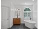 Bright bathroom with a freestanding tub, wooden vanity, and arched window with shutters at 1426 Doe Ridge Ln, Fort Mill, SC 29715