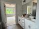 Bathroom featuring double sinks, white cabinets, and a large mirror; bedroom view in the background at 1453 Ardmore Dr # 240, Sherrills Ford, NC 28673