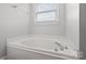 Bright bathroom featuring a soaking tub with chrome fixtures under a window with white blinds at 2082 Egret Ct, Rock Hill, SC 29732