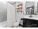 Modern bathroom with black vanity, open shelving, and a shower with gray tile at 5501 Joyce Dr, Charlotte, NC 28215