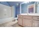 Bright bathroom featuring a vanity with a pink cabinet, a mirror with vanity lights, and a tub with white tiles at 5807 Mctaggart Ln, Charlotte, NC 28269