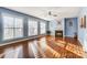 Spacious living room with hardwood floors, fireplace, ceiling fan, and natural light streaming through large windows at 5807 Mctaggart Ln, Charlotte, NC 28269