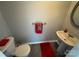 Practical half bath featuring a toilet and pedestal sink, enhanced by a red accent towel and rug at 8603 Westhope St, Charlotte, NC 28216