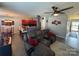 Open-concept living room featuring a gray sectional, ceiling fan, red accent pieces, and an eat-in kitchen at 8603 Westhope St, Charlotte, NC 28216