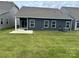 Spacious backyard with lush lawn, patio and the home's exterior featuring dark siding and white trim at 1032 Barnette Farm Ln, Monroe, NC 28110