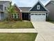 Charming single-story home featuring a brick and navy blue facade, attached garage, and manicured lawn at 1032 Barnette Farm Ln, Monroe, NC 28110