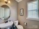 Stylish powder room featuring an oval mirror, decorative sink, and neutral wall tones at 10547 Skipping Rock Nw Ln, Concord, NC 28027