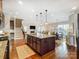 Open-concept kitchen with dark wood cabinets, granite counters, stainless appliances, and island with seating at 10547 Skipping Rock Nw Ln, Concord, NC 28027
