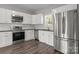 Well-lit kitchen with stainless steel appliances, white cabinets, and dark countertops at 106 Desert Sky Ct, Statesville, NC 28625