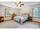 A bright bedroom with neutral walls, carpet, two windows, and a ceiling fan at 1119 Palmyra Dr, Tega Cay, SC 29708