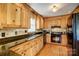 Spacious kitchen with wood cabinets, granite counters, hardwood floors, and black appliances at 1119 Palmyra Dr, Tega Cay, SC 29708