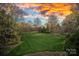 Expansive backyard with a manicured lawn, trees, and a beautiful sky at sunset at 19117 Davidson Concord Rd, Davidson, NC 28036