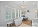 Bright bathroom featuring a soaking tub, chandelier, chair, and large window at 19117 Davidson Concord Rd, Davidson, NC 28036