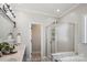 Bright bathroom with a large mirror, double vanity, and glass-enclosed shower, featuring modern fixtures and a neutral color palette at 2508 Shaggy Bark Ct, Belmont, NC 28012