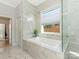 Luxurious marble bathroom features a soaking tub, separate shower, and a window overlooking the backyard at 3301 Mountainbrook Rd, Charlotte, NC 28210