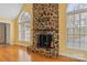 A close up of the fireplace with stone surround, hearth, and wood mantel, flanked by large arched windows at 3772 Sandy Ford Rd, Hickory, NC 28602