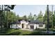 Exterior of a bright modern home with black trim, lush landscaping, and a two-car garage surrounded by trees at 3A Riverlane Rd, Rock Hill, SC 29730