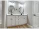 Modern bathroom featuring a double vanity with oval mirrors and wood-look floors at 437 Cedar Grove Rd, Clover, SC 29710